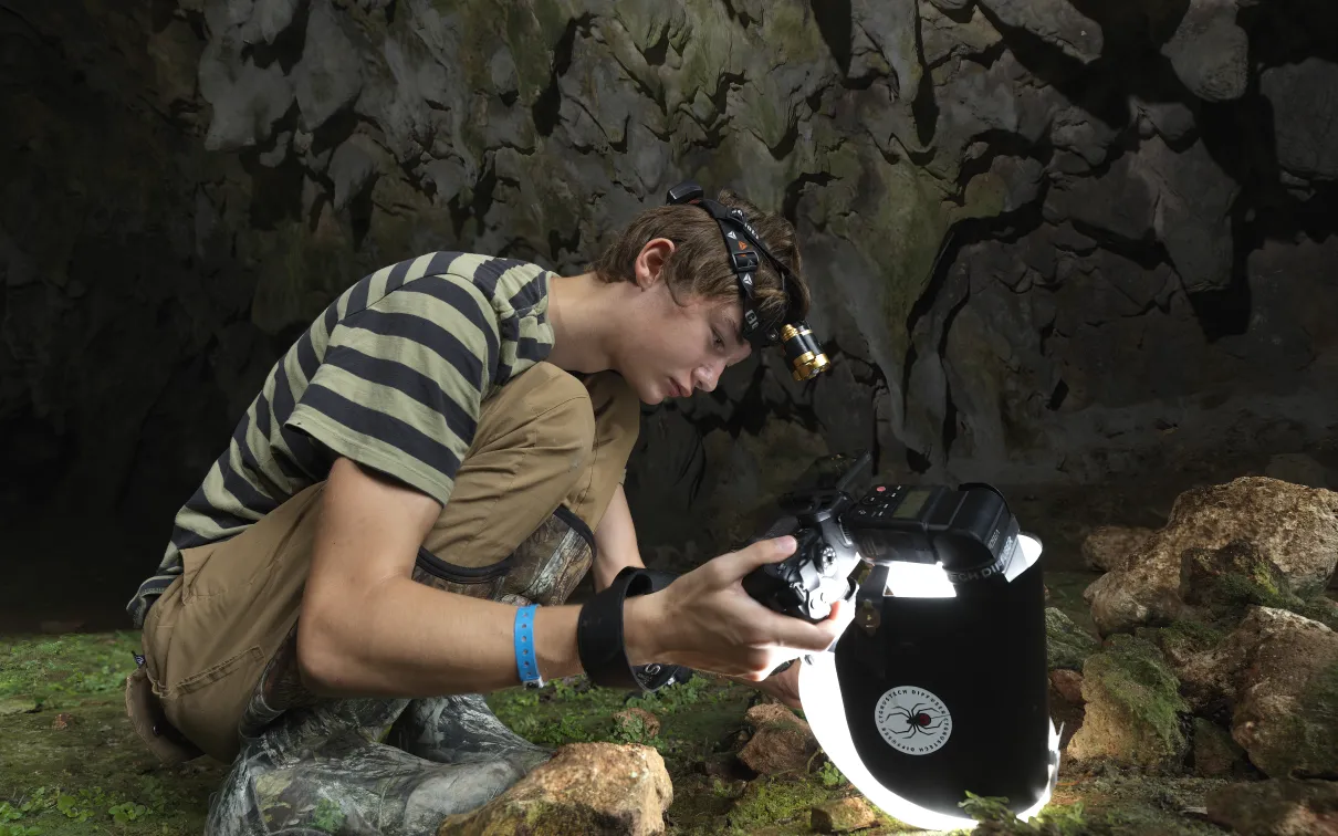 Beckett Robertson, deep inside a cave in the Dominican Republic, where he captured his award-winning photo of a whip spider. (2023)