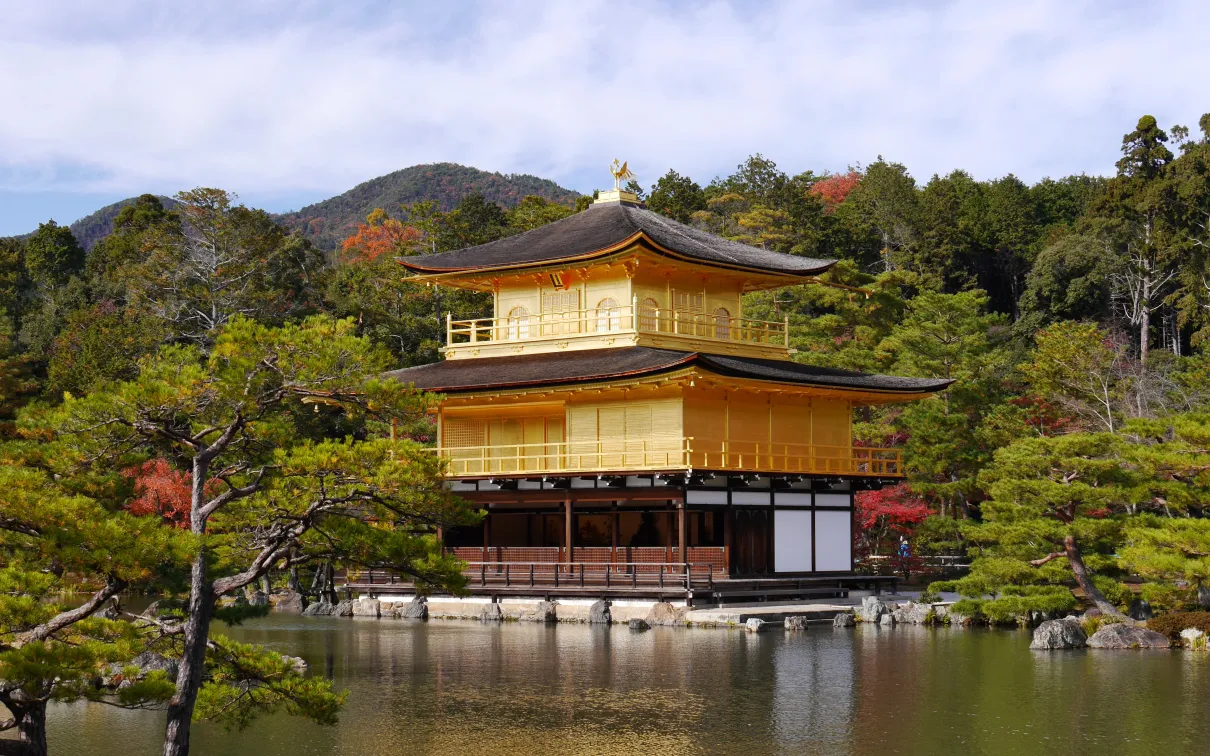 A golden pagoda-style building on the shore of a lake.
