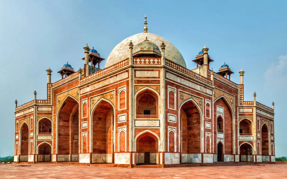 A large red brick building with palm trees in the foreground