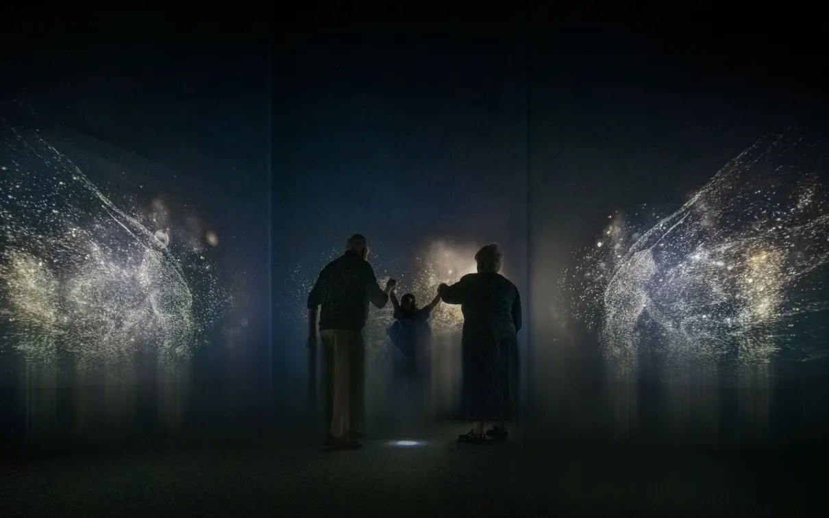 Two adults and a child experiencing the immersive exhibition.