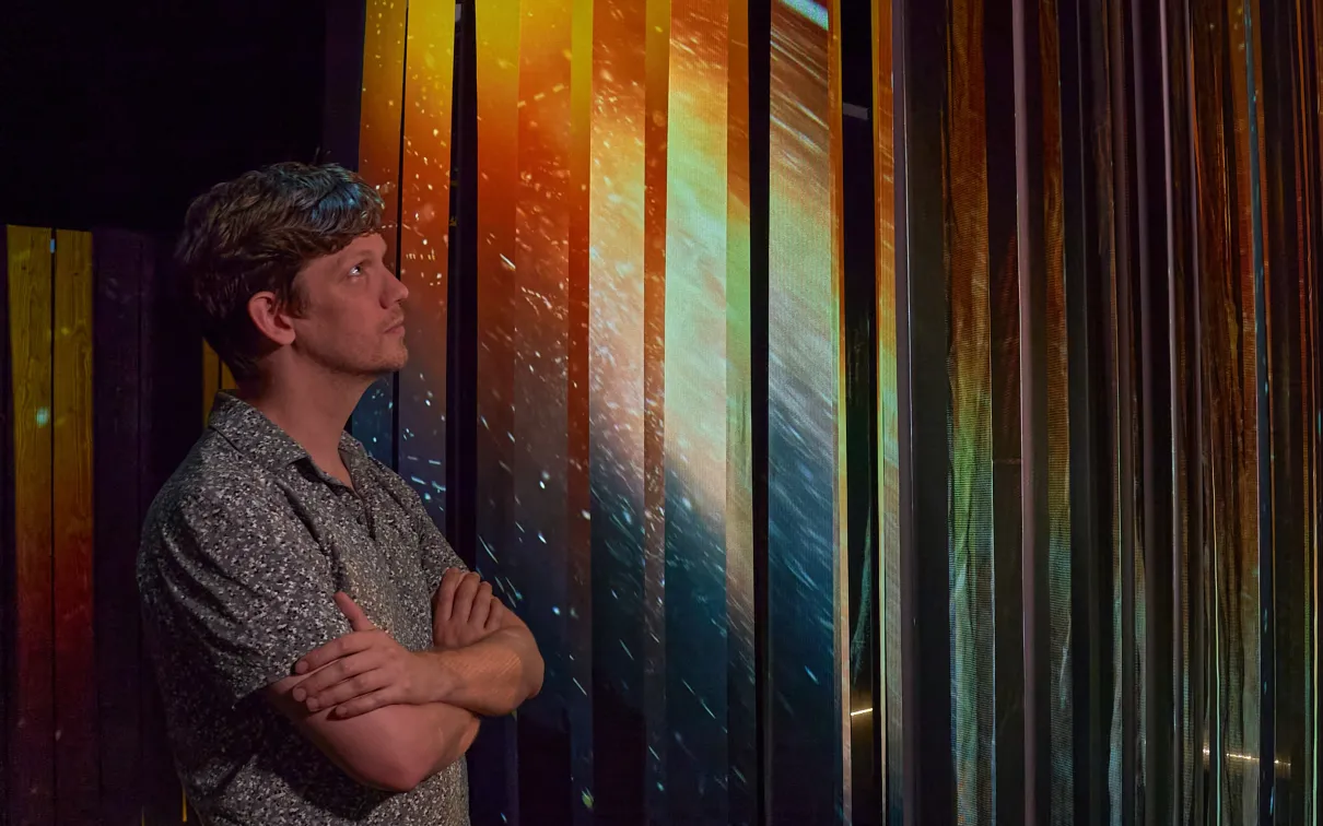A person experiences light playing off tall vertical panels.