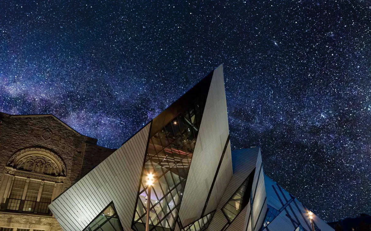 A museum is silhouetted against a dark sky full of brilliant stars