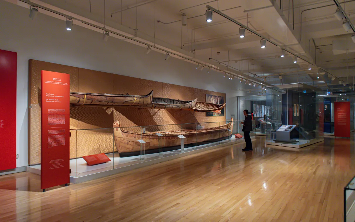 A man standing in front of a display of four birchbark canoes.