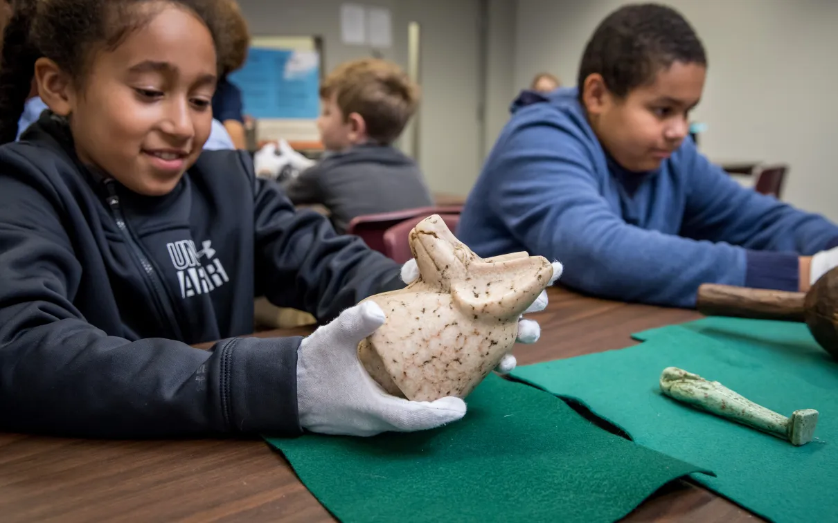A student holds an ancient Egyptian canopic jar lid.