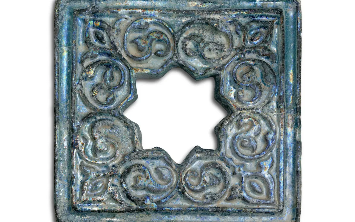 A tile featuring an open eight-pointed star in the centre surrounded by scrollwork resembling palms.