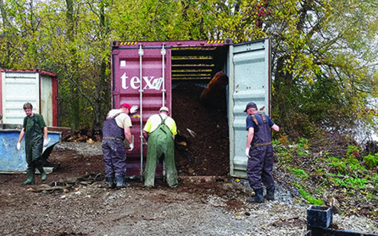Three men working next to a shipping container that contains the Blue Whale bones and manure.
