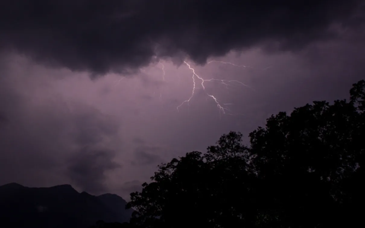 A bolt of lightning streaks across a purple sky over the mountains and rainforests of Sri Lanka
