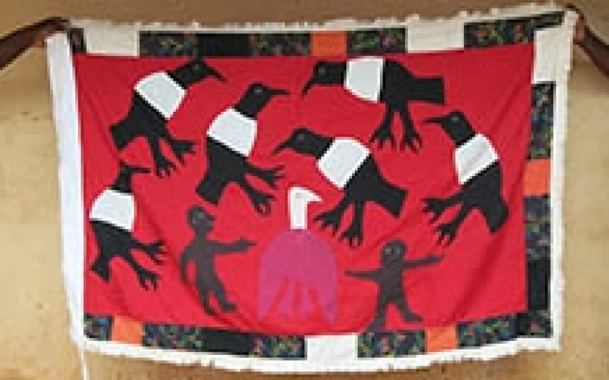 People holding up a handmade flag depicting birds.
