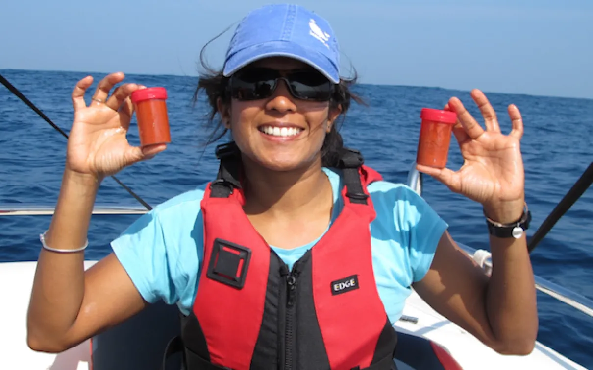 Asha de Vos, P.h.D. holds two bottles of freshly collected blue whale poop off the coast of Sri Lanka. Photo Credit: Oceanswell
