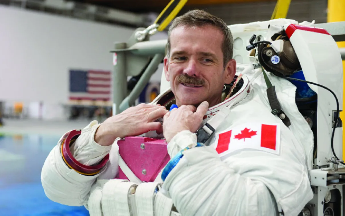 A photograph of a man in an astronaut suit without a helmet

