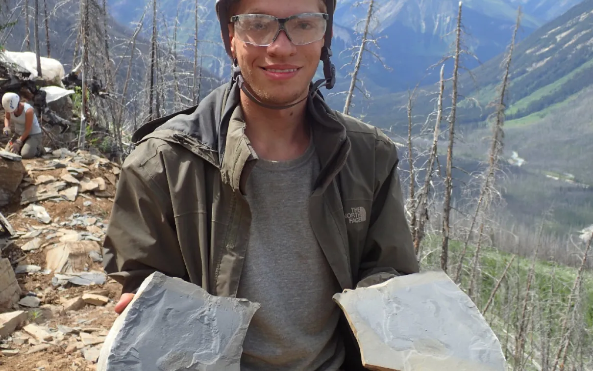 Un étudiant tient des plaques de schiste contenant des fossiles.
