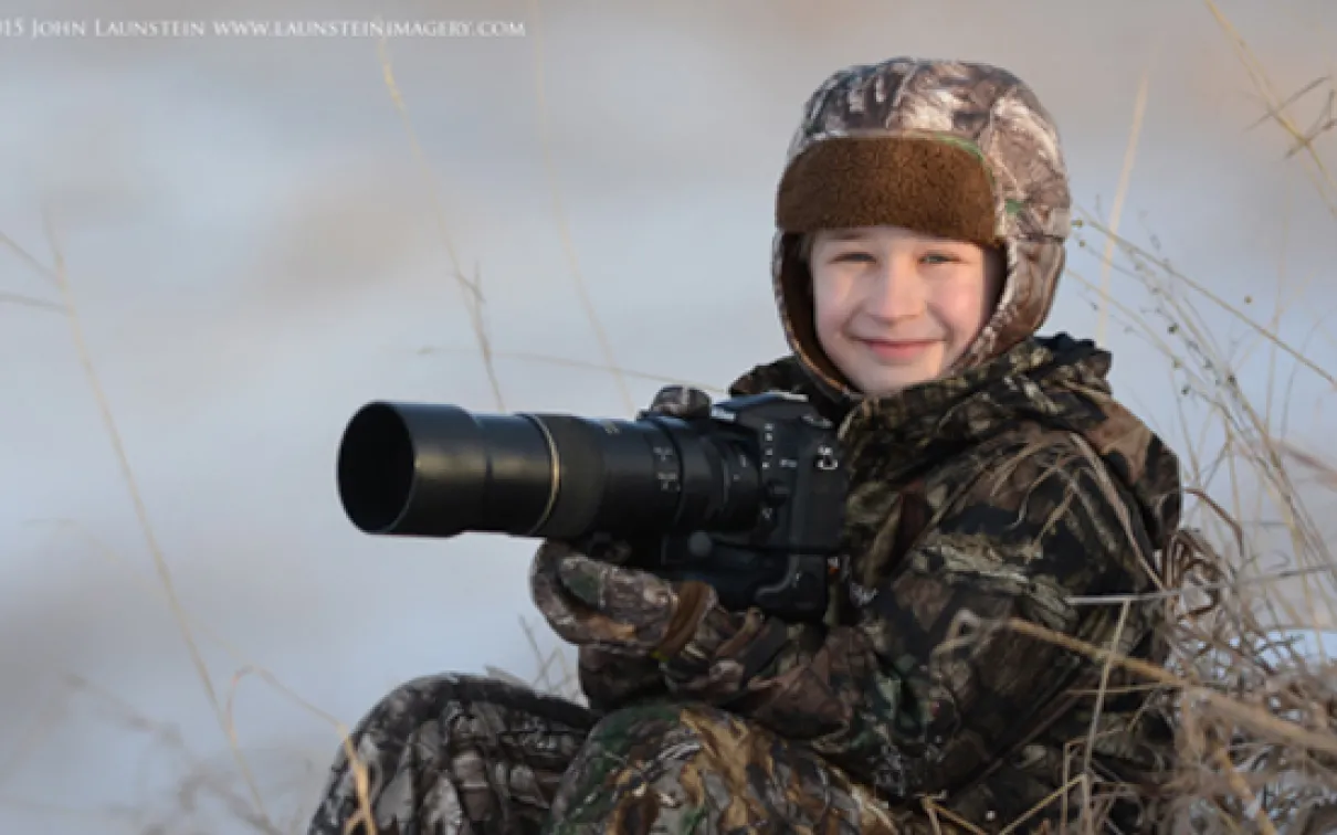 Ten-year-old wildlife photographer Josiah Launstein sits bundled up and ready to take the shot.
