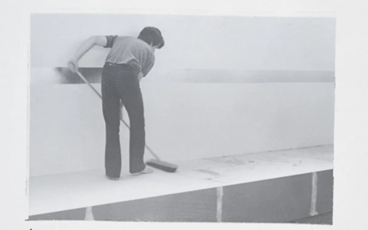 Black and white photo of a man mopping a platform
