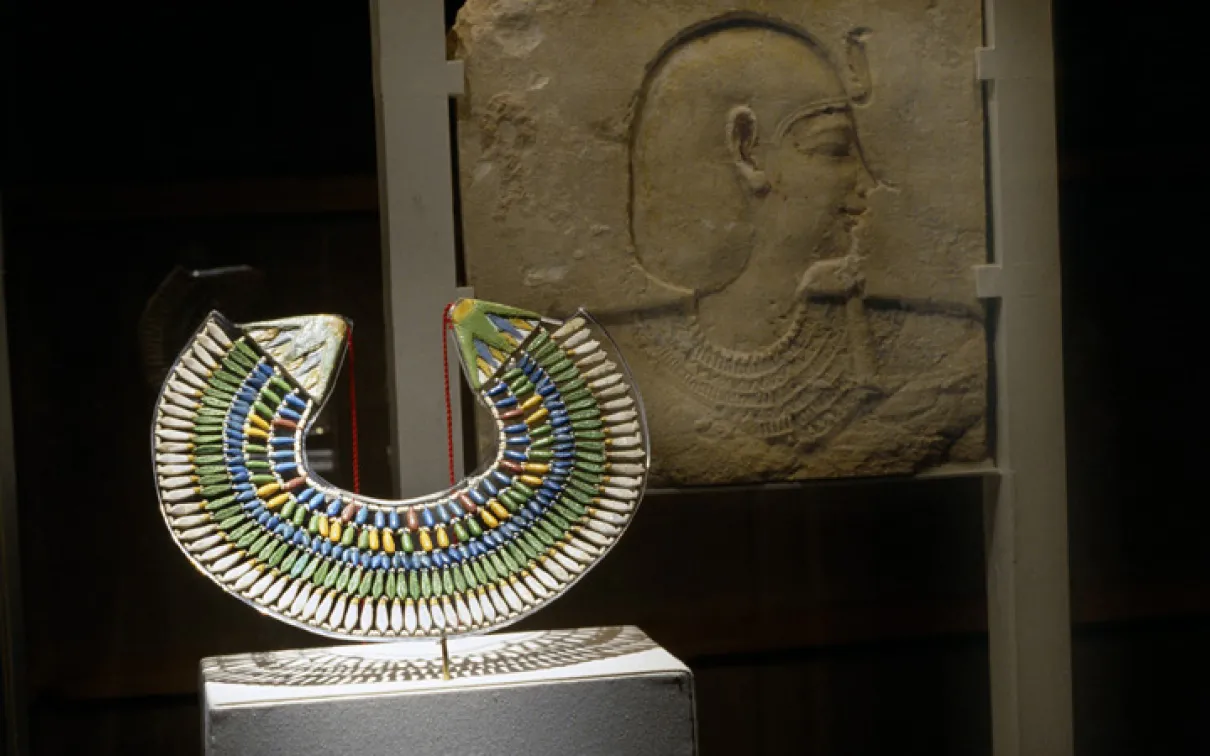 Gallery shot of Eye of the Beholder with collar and relief sculpture in foreground under spotlight, W. Garfield Weston Exhibition Hall
