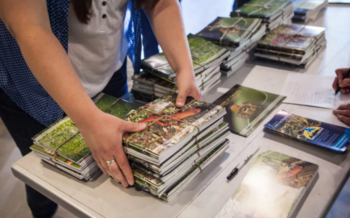 Un bénévole rassemble une pile de livres de la Toronto Biodiversity Series sur une table.
