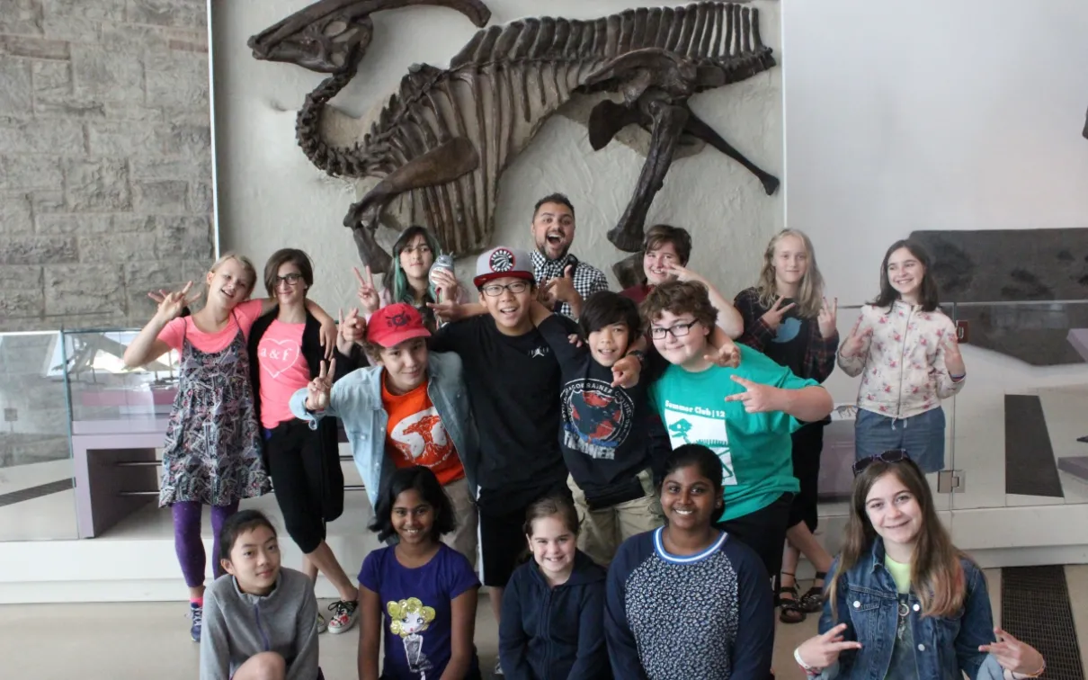A group of happy campers in front of the Museum's famous Parasaurolophus.