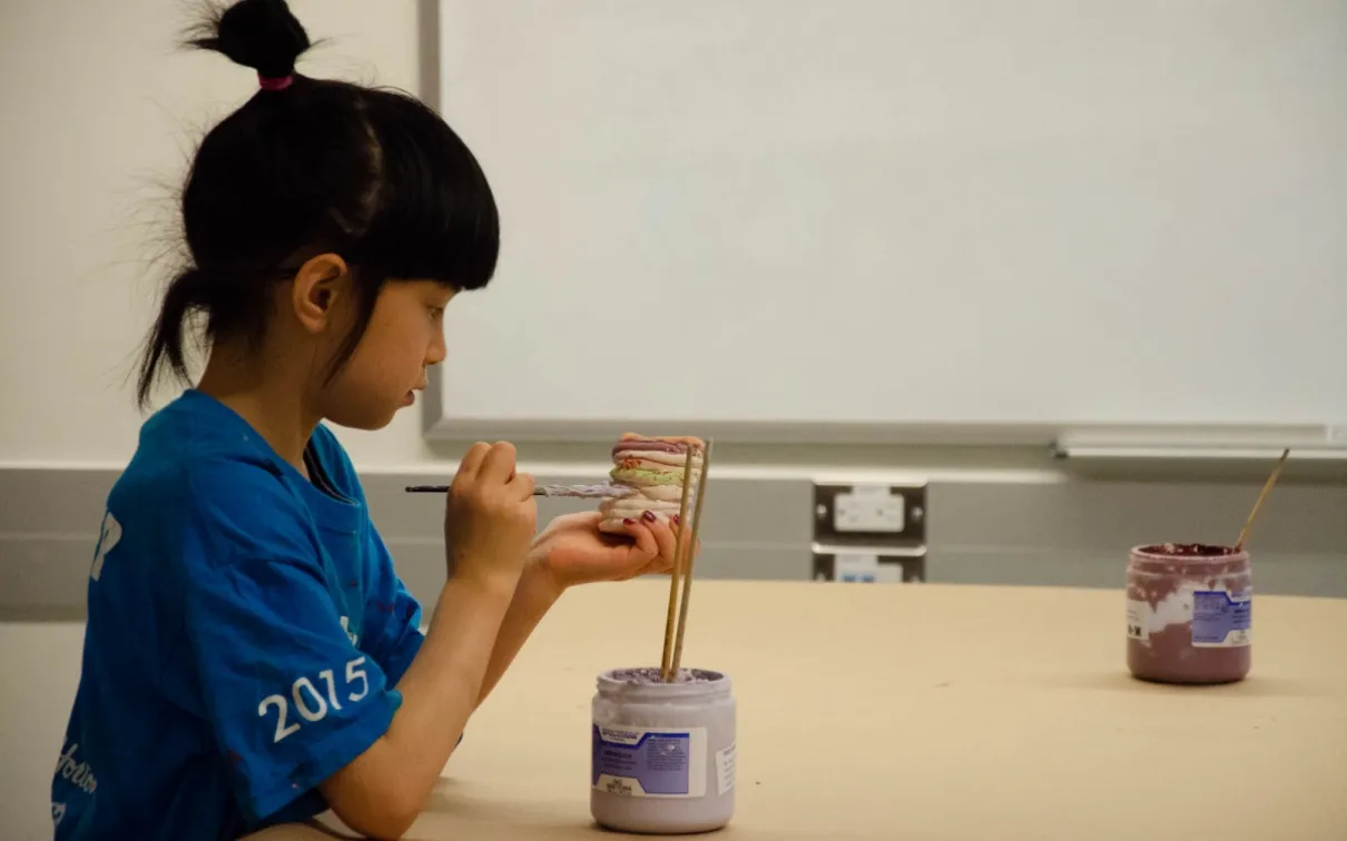 A student paints her ceramic pot in class. Image: Michael Berger