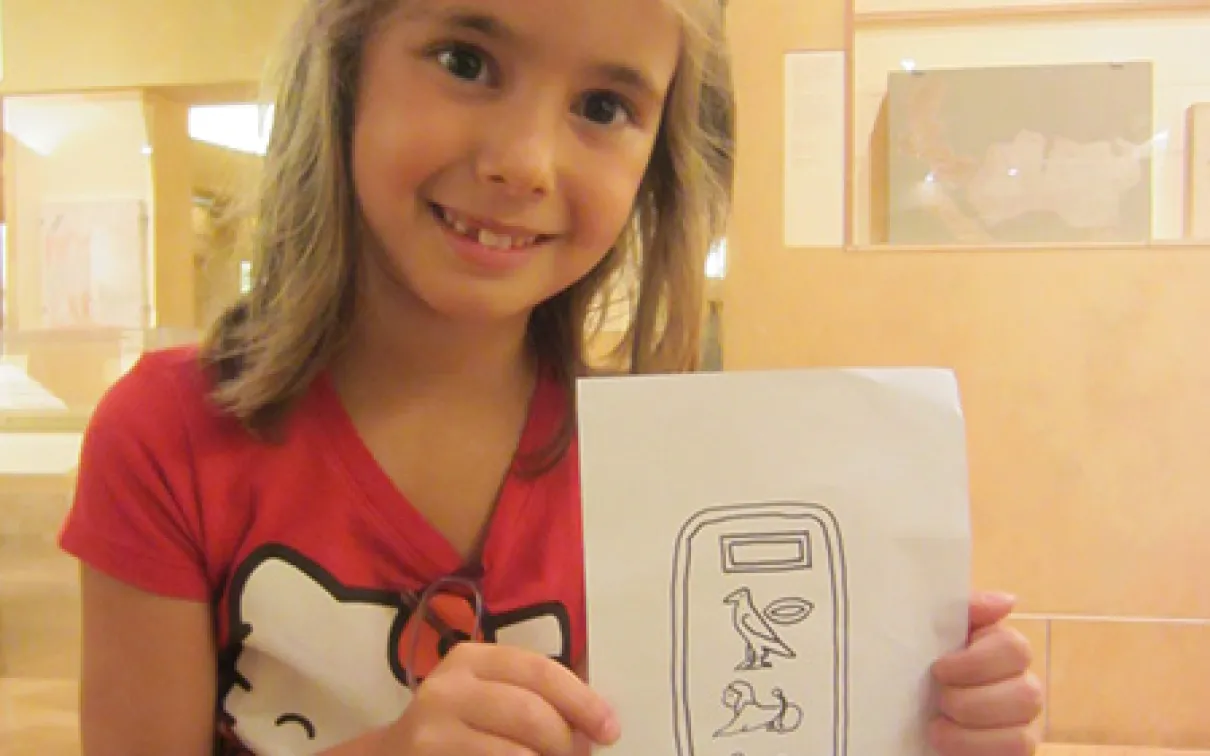 A girl holds a drawing of Egyptian Heiroglyphs
