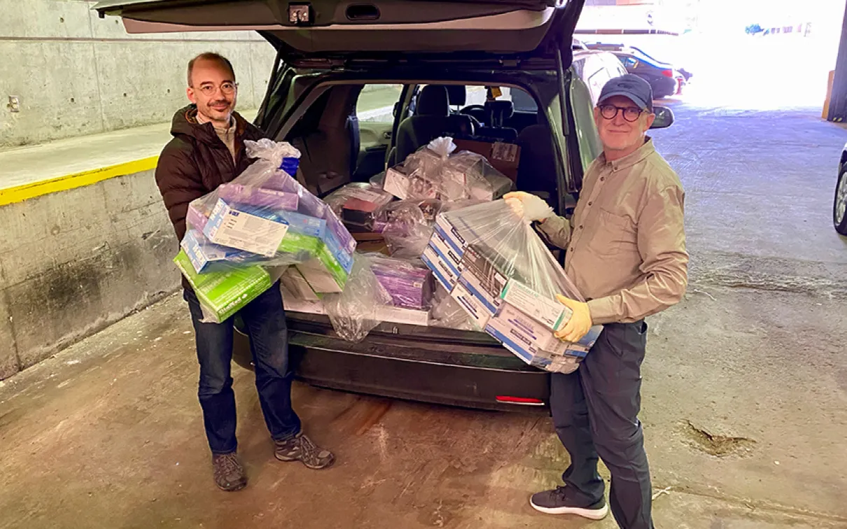 Two ROM staff load an SUV with PPE.