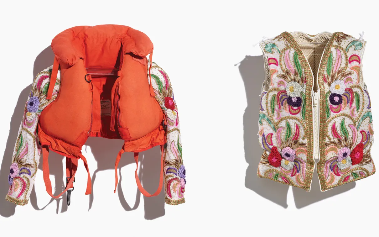 Image of an adult and a child's repurposed life jackets, the adult's completely covered, and the child's embellished with added sleeves, in a colourful beaded fabric depicting a floral pattern in reds, pinks, greens, and gold. Side-by-side image of both jackets taken on a white background.
