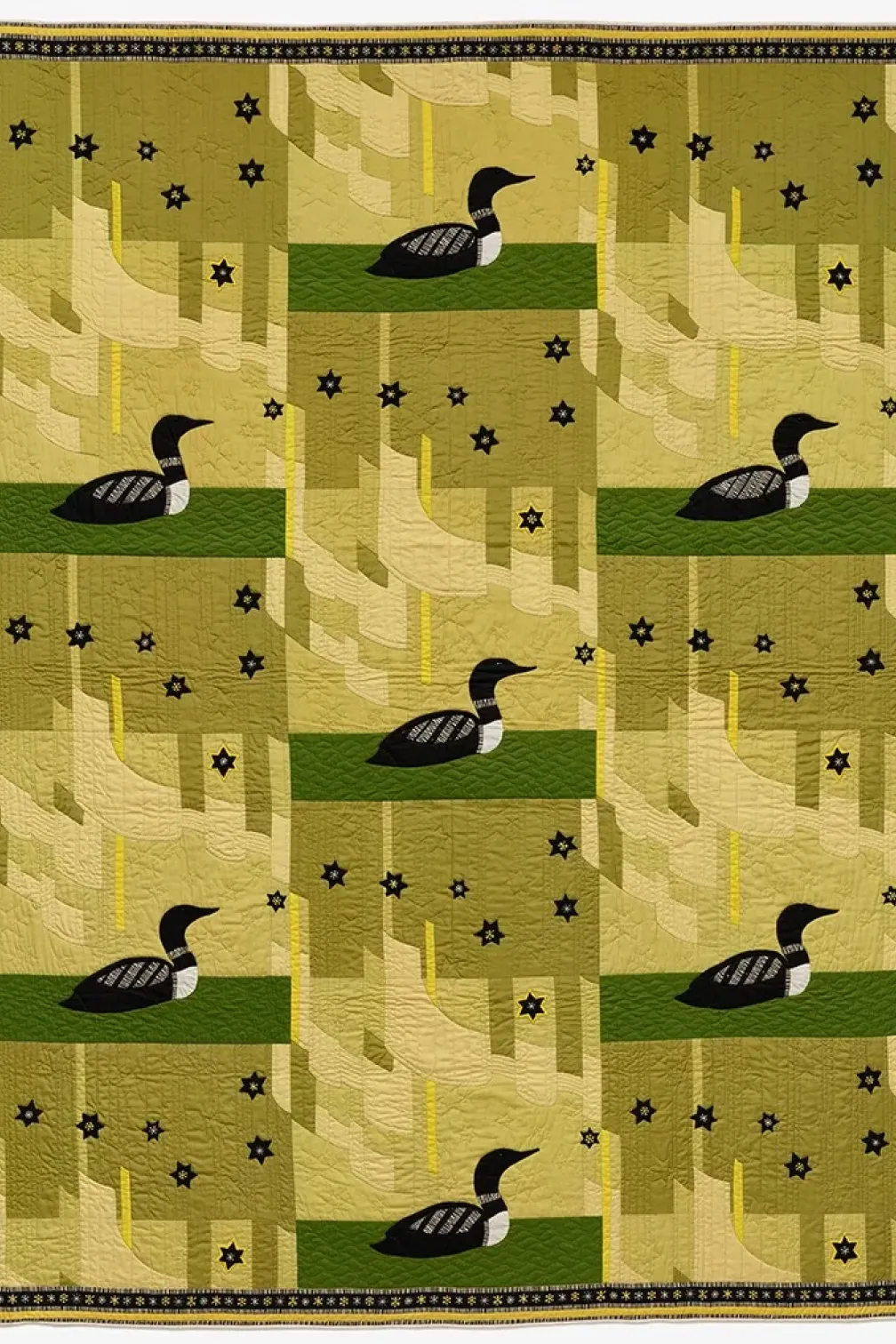 A quilt featuring a duck design set against a vibrant green background, showcasing intricate stitching and colorful patterns.