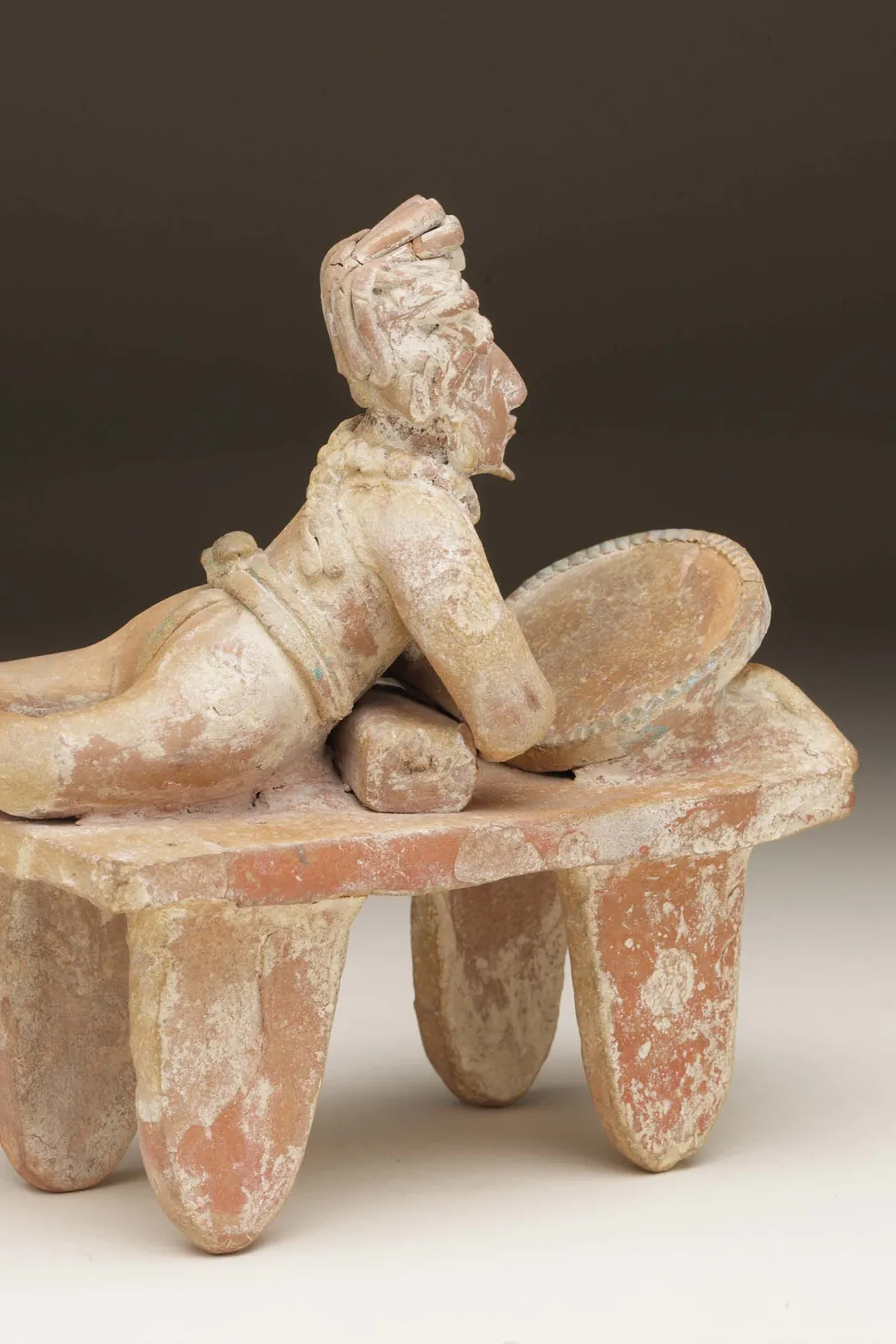 Statue en argile représentant un noble allongé se regardant dans un miroir.