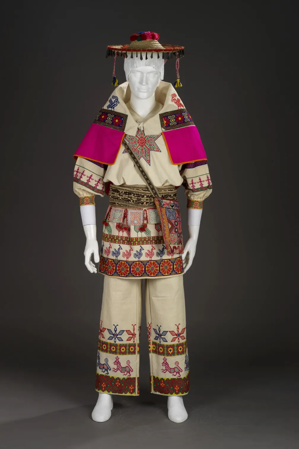 Un mannequin portant une tenue crème avec des broderies colorées.