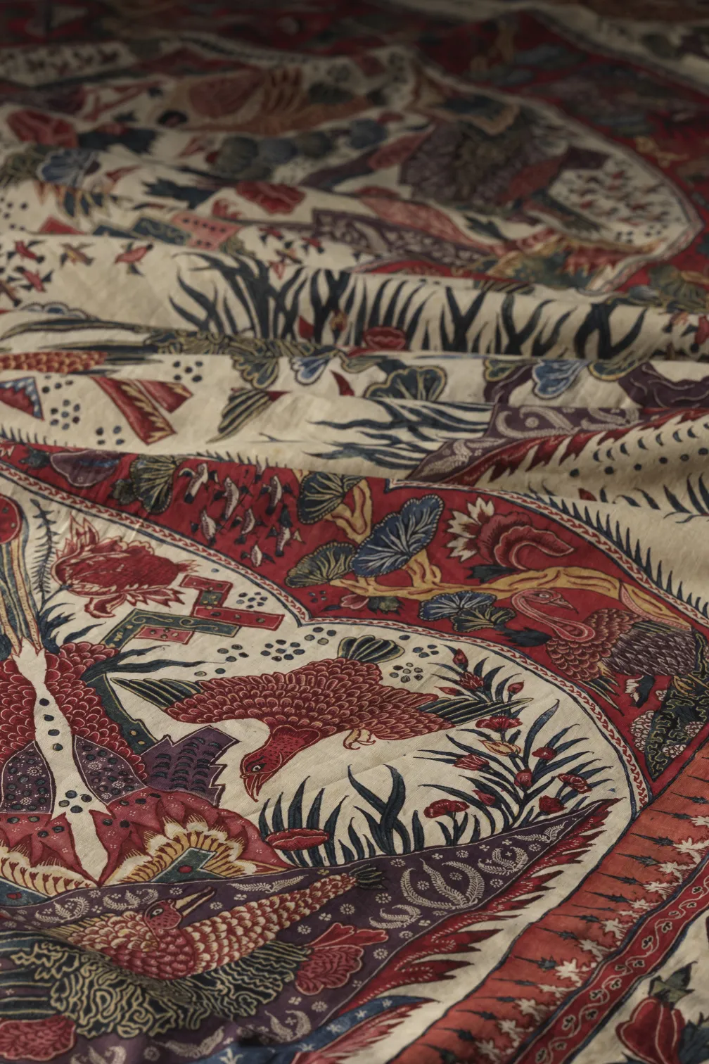  A close-up of red and black fabric featuring an intricate bird design, showcasing vibrant colors and detailed patterns.