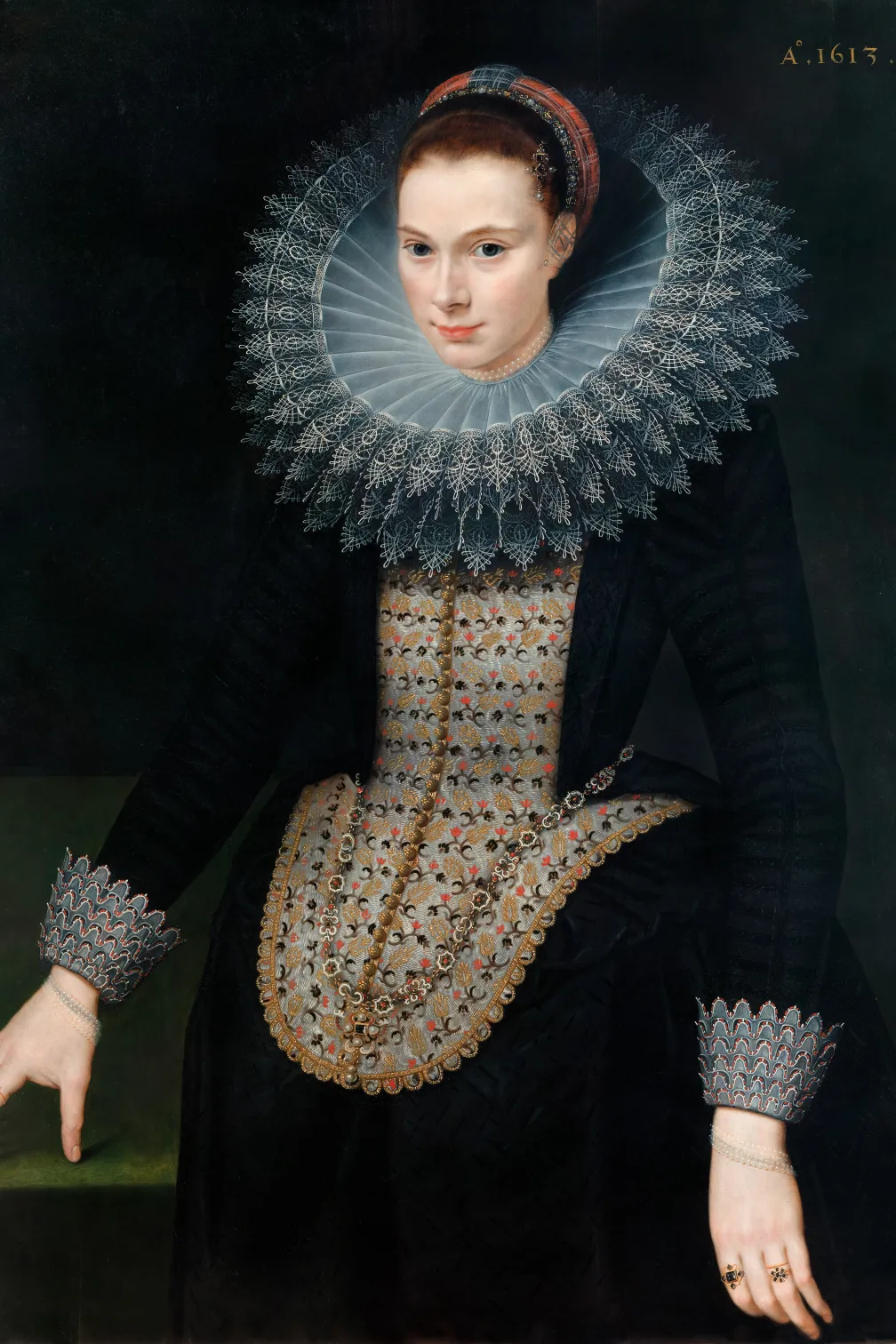 Portrait of a woman in a black dress with a large white lace "ruff" collar, on a black background.