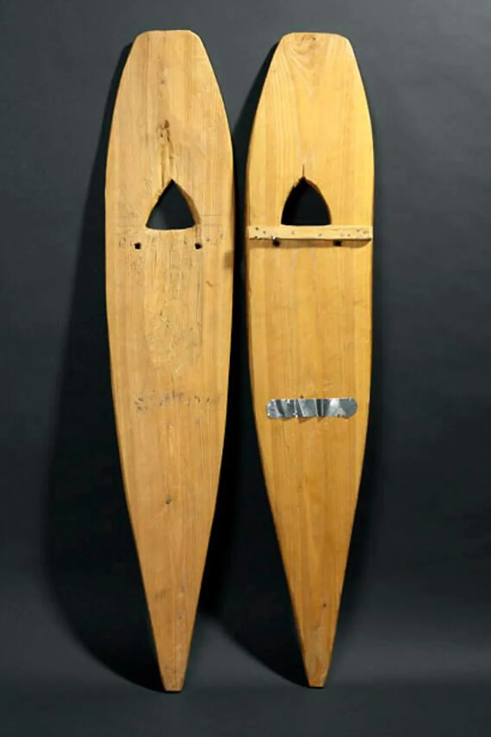 Two snowshoes made of pale wood carved into an oblong shape with pointed ends.
