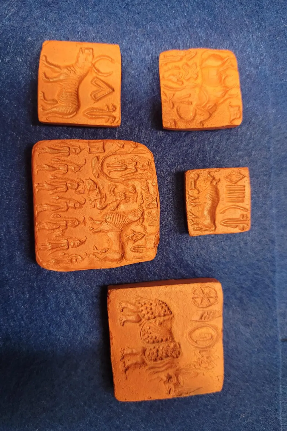 Five orange square seals of various sizes. Each orange square seal has various symbols and images engraved into them.