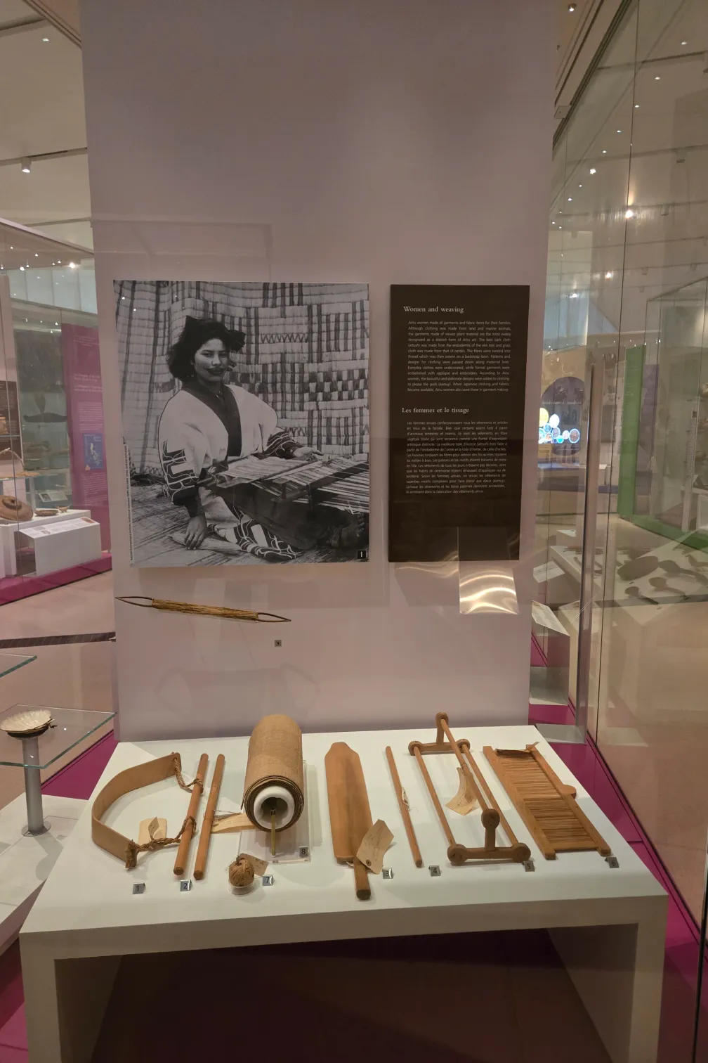 A case in a museum gallery holds a variety of wooden weaving tools.