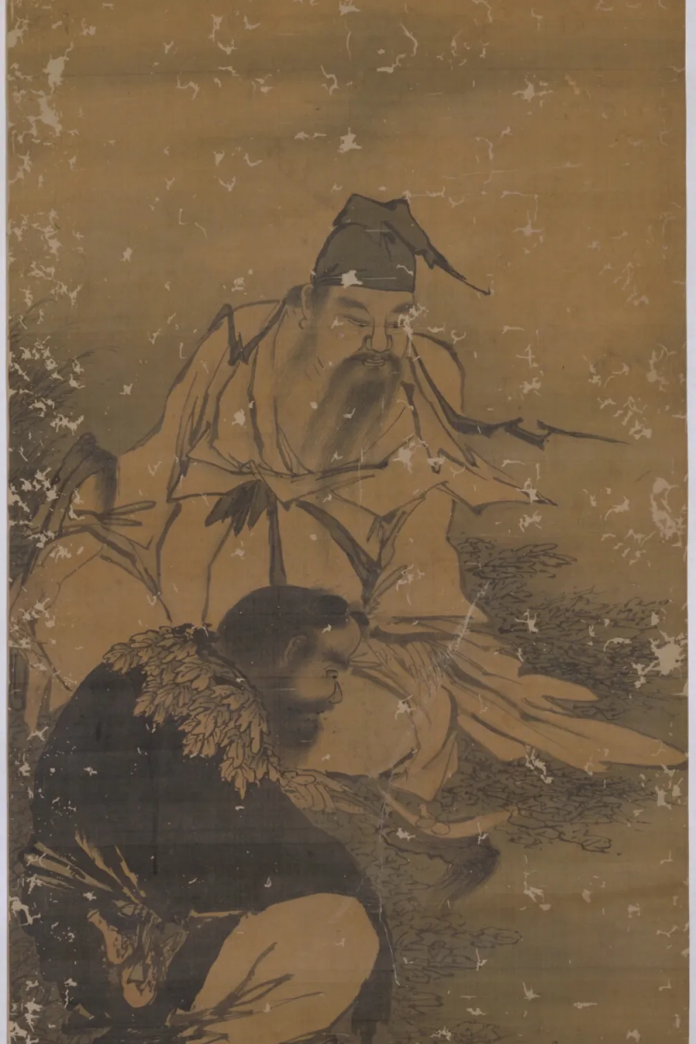 Vertical ink-and-wash painting on a tan, aged scroll. Two human figures in flowing robes are shown outdoors among grasses and rocks; one figure stands or leans forward holding long, leafy branches, while another figure crouches below with a hunched posture. The style is monochrome linework with light ink washes, visible wear, and scattered patches of abrasion across the surface.