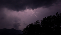 A bolt of lightning streaks across a purple sky over the mountains and rainforests of Sri Lanka