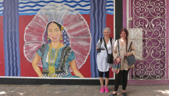 Photo of two women standing against a colourful mural