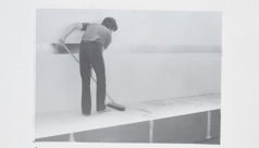 Black and white photo of a man mopping a platform