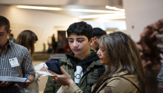 Teenage boy reads the ROM MagnusCards on a smartphone held by his mother
