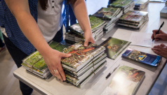 A volunteer gathers a stack of Toronto Biodiversity Series books on a table