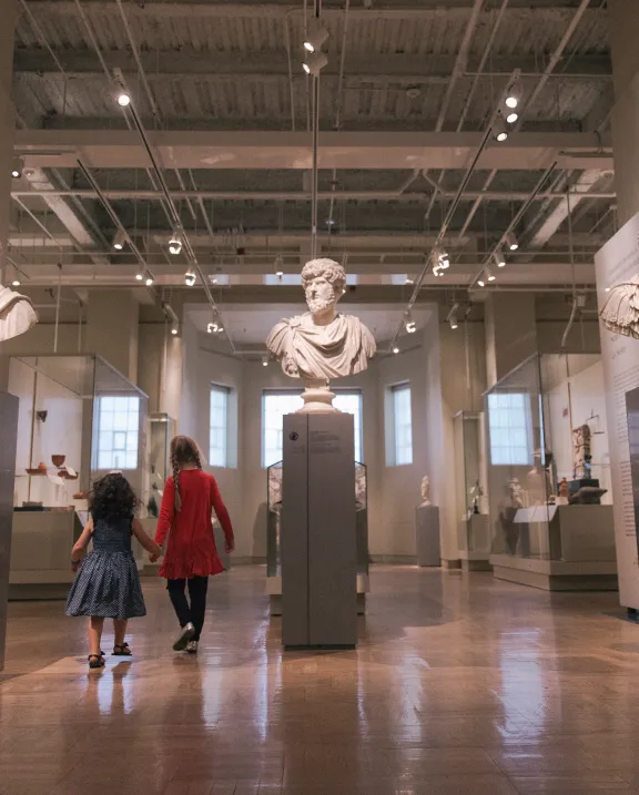 two people walking through the Roman portrait display in the Gallery of Rome.