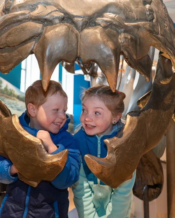 Two children look out from the mouth of the Dunkleosteus in the Dawn of Life Gallery