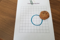 Biscuit aux brisures de chocolat sur du papier quadrillé, cure-dents et trombone, cercle indiquant les contours du biscuit à côté 
