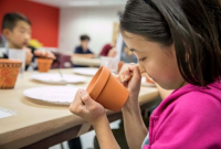 Student in the ROM Makerspace drawing with pencil on a clay pot