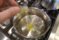 Yellow food colouring being mixed into boiling sugar solution.