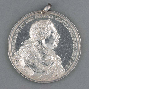 photo of a silver medal with a face in profile