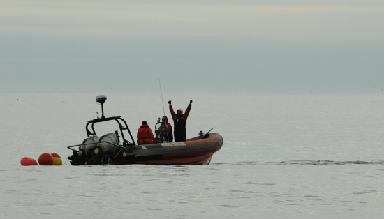 Zodiac boat on the ocean with researchers looking toward the photographer.
