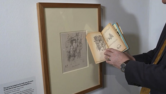 Julius Bryant holding a Winnie-the-Pooh book in front of a framed illustration.