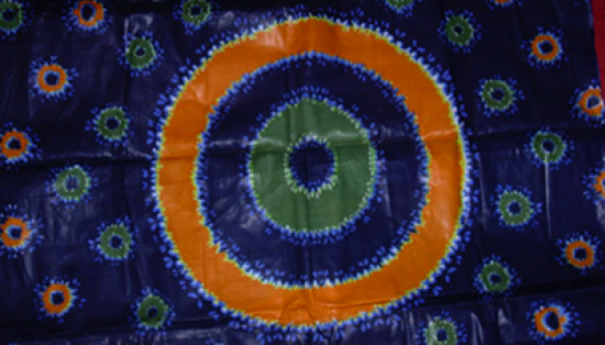 Cotton with a pattern of green and orange rings on a deep blue background. 