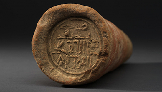 A clay cone with Egyptian hieroglyphs stamped on the flat face.