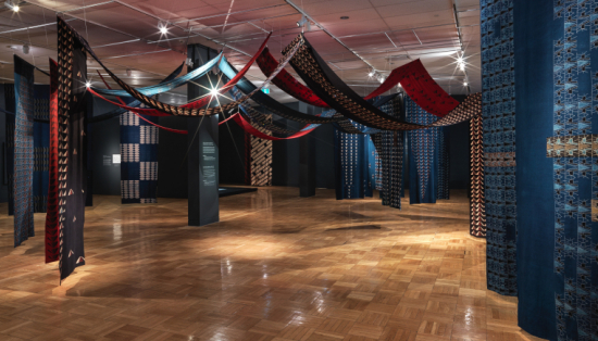 Panoramic view of a soft sculpture installation consisting of lengths of printed cotton fabric suspended from above.