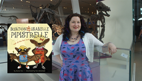 A woman stands in front of a room full of dinosaur skeletons, next to the illustrated cover of “Burton and Isabelle Pipistrelle.”